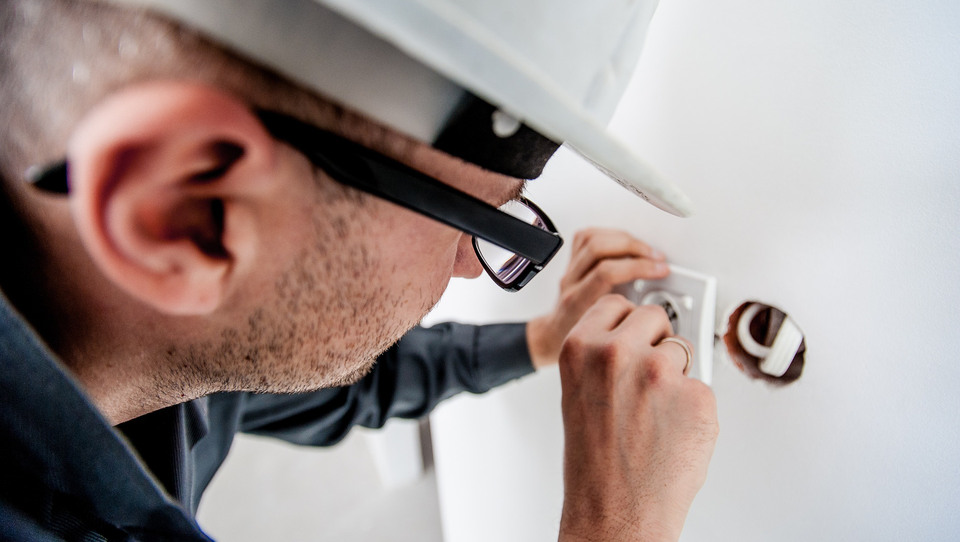 An electrician mounts an electrical outlet.